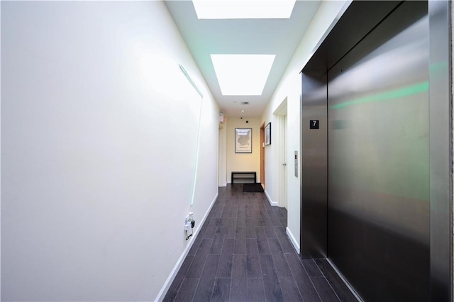 hallway with dark hardwood / wood-style flooring, a skylight, and elevator