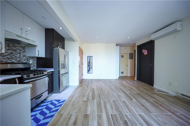 kitchen featuring an AC wall unit, white cabinetry, backsplash, stainless steel appliances, and light wood-type flooring