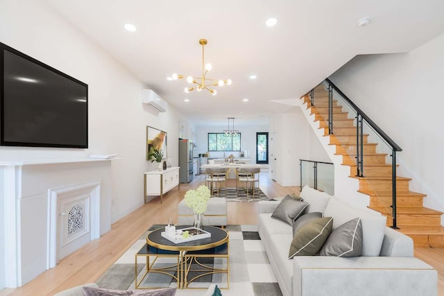 living room with a wall unit AC, sink, a chandelier, and light wood-type flooring