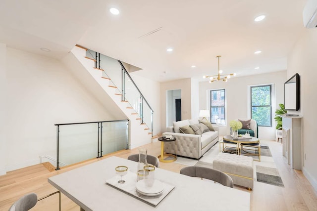 living room with a notable chandelier, a wall mounted AC, and light wood-type flooring