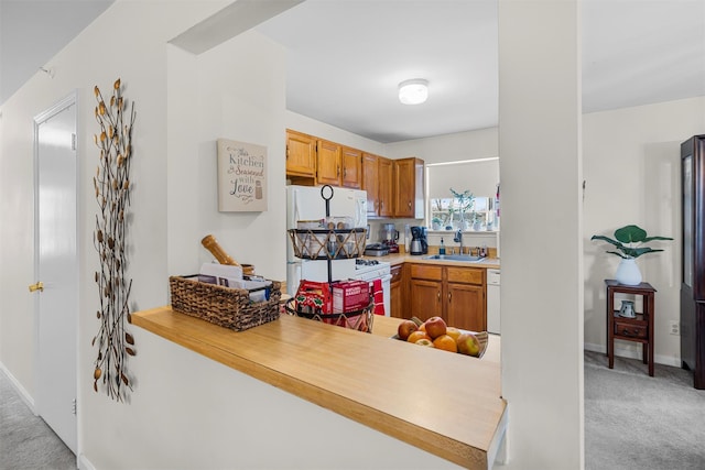 kitchen with white appliances, light carpet, a sink, and a peninsula