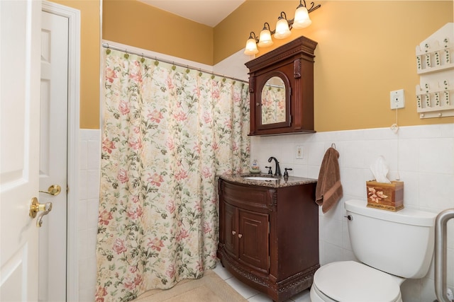 bathroom featuring toilet, wainscoting, vanity, and tile walls