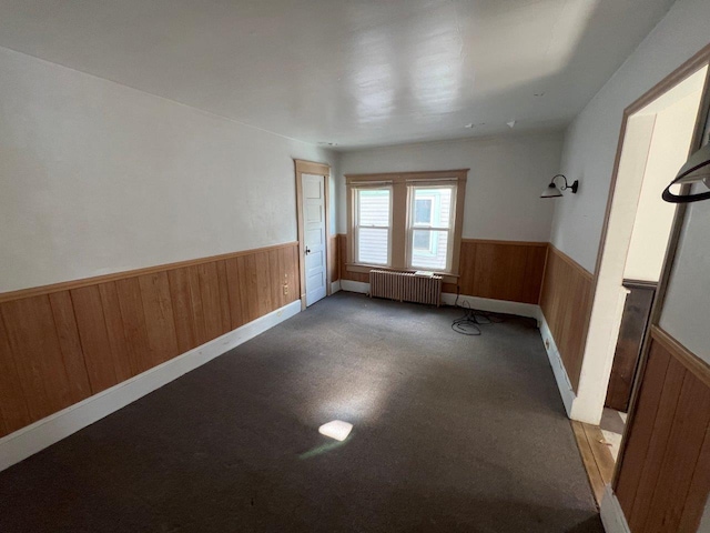 empty room with radiator heating unit and wood walls