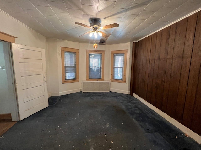 entrance foyer with ceiling fan, radiator heating unit, and wood walls