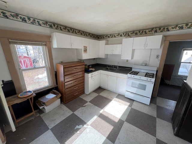 kitchen featuring sink, gas range gas stove, and white cabinets