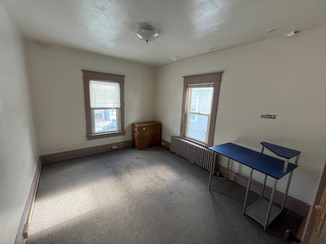 interior space featuring radiator heating unit and dark colored carpet