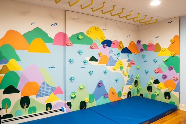 playroom featuring wood-type flooring and a baseboard heating unit