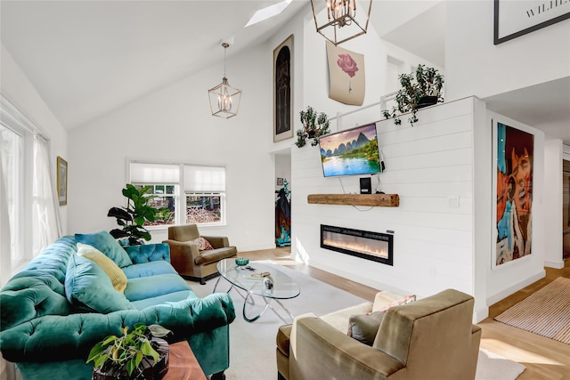 living room featuring high vaulted ceiling, a healthy amount of sunlight, an inviting chandelier, and light wood-type flooring