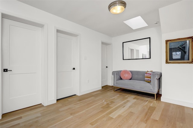 sitting room with light hardwood / wood-style floors and a skylight