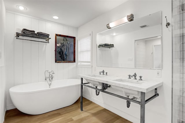 bathroom with a bath, wood-type flooring, and dual sinks