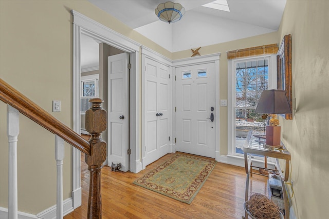 entryway with light hardwood / wood-style flooring and vaulted ceiling with skylight