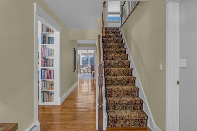 staircase with hardwood / wood-style flooring and a baseboard heating unit