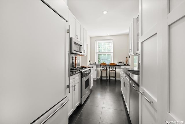 kitchen with white cabinetry, dark tile patterned flooring, and appliances with stainless steel finishes