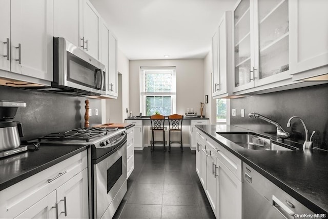 kitchen with dark tile patterned floors, white cabinetry, appliances with stainless steel finishes, and sink