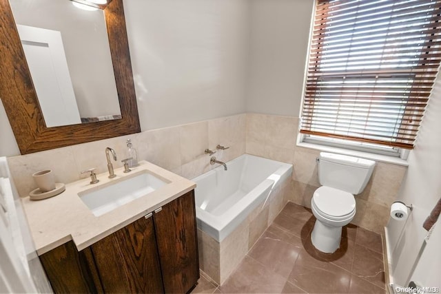 bathroom with tile patterned floors, toilet, tile walls, vanity, and a relaxing tiled tub