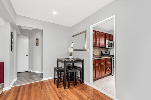 kitchen with light wood-type flooring, stainless steel appliances, backsplash, and sink