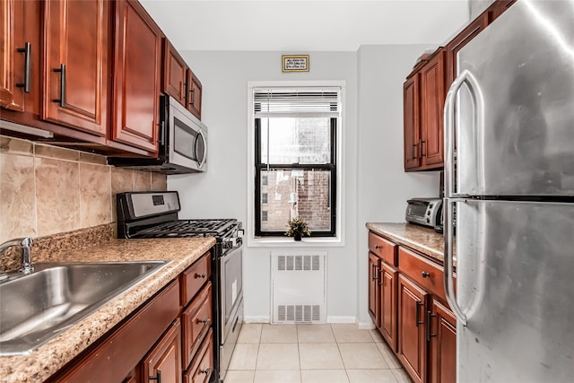 kitchen featuring light stone countertops, sink, light tile patterned floors, appliances with stainless steel finishes, and decorative backsplash