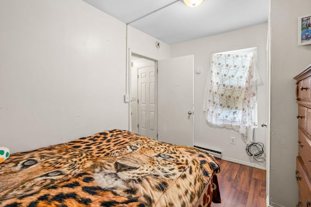 bedroom with dark hardwood / wood-style flooring and a baseboard heating unit