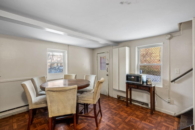 dining space featuring beamed ceiling, a baseboard heating unit, and dark parquet floors