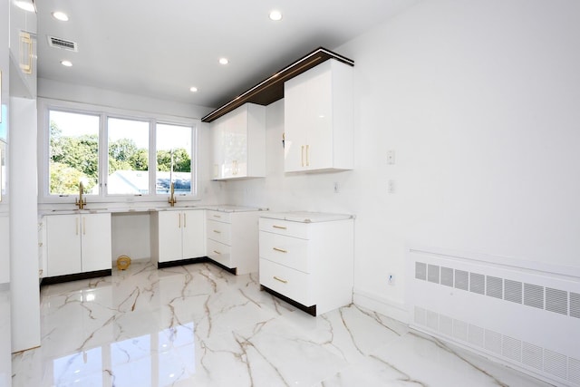 kitchen featuring sink, radiator heating unit, and white cabinets