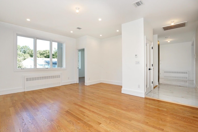 empty room featuring radiator heating unit and light wood-type flooring