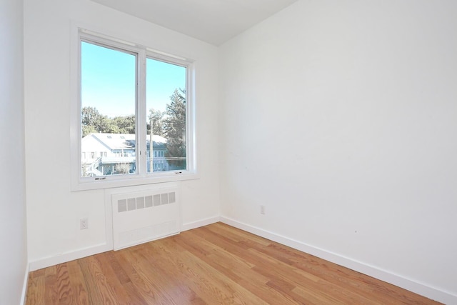 spare room with radiator heating unit and light wood-type flooring