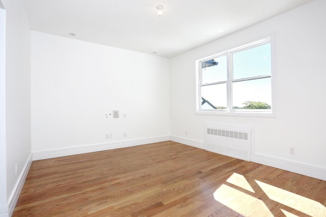 unfurnished room with radiator and hardwood / wood-style floors