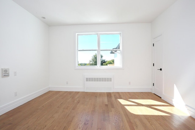 spare room featuring radiator and light wood-type flooring