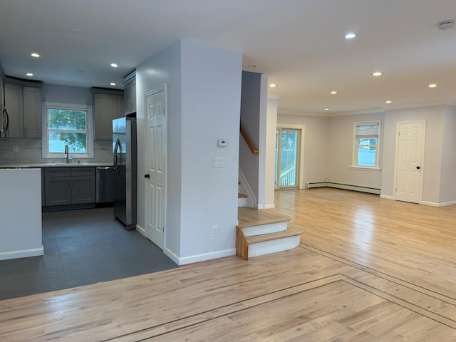 kitchen with sink, baseboard heating, stainless steel refrigerator, gray cabinets, and decorative backsplash