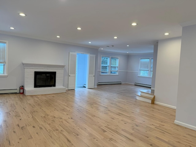 unfurnished living room with ornamental molding, a brick fireplace, baseboard heating, and light hardwood / wood-style flooring