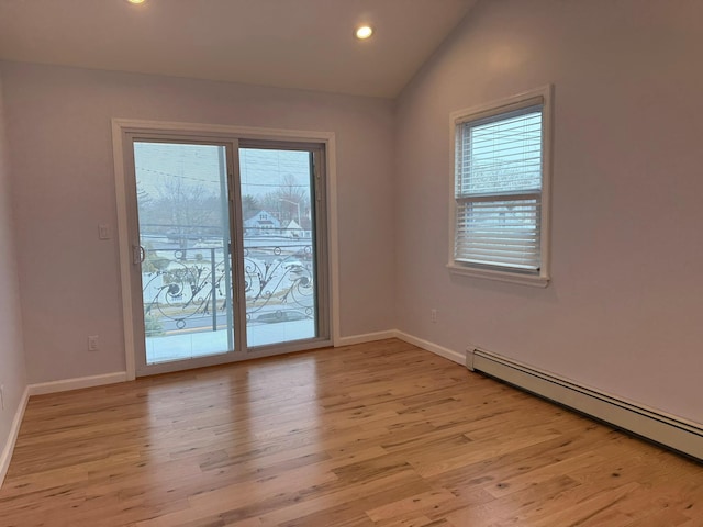 unfurnished room with baseboard heating, vaulted ceiling, and light wood-type flooring