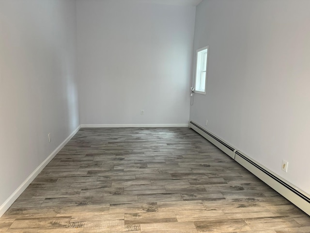 unfurnished room featuring a baseboard heating unit and light wood-type flooring