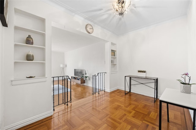 hallway featuring baseboards, built in features, ornamental molding, and an upstairs landing