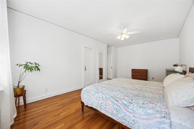 bedroom with a ceiling fan, baseboards, and wood finished floors