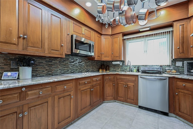 kitchen with tasteful backsplash, sink, light tile patterned floors, light stone counters, and stainless steel appliances