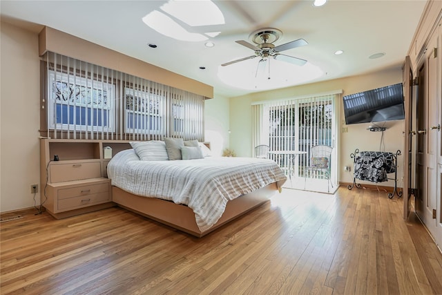 bedroom featuring a skylight, access to outside, multiple windows, and light wood-type flooring