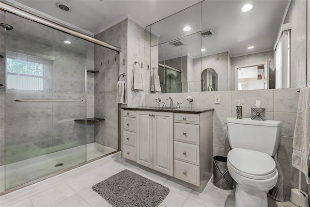 bathroom featuring vanity, toilet, a shower with shower door, and tile walls