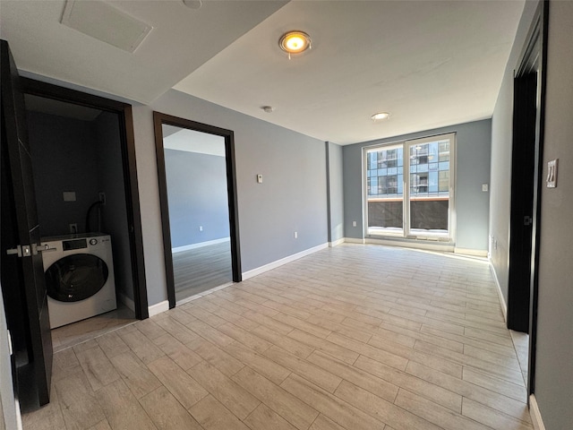 unfurnished room featuring washer / clothes dryer and light hardwood / wood-style floors