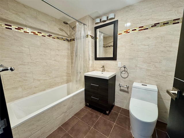 full bathroom with shower / tub combo with curtain, tile patterned flooring, tile walls, vanity, and toilet