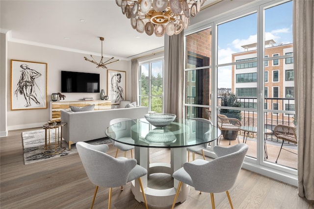 dining space with a notable chandelier, crown molding, and light wood-type flooring