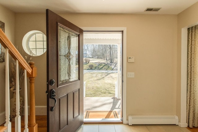 doorway with a baseboard heating unit, visible vents, baseboards, and stairs