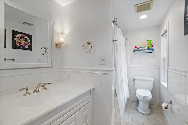 full bathroom with toilet, a wainscoted wall, visible vents, and vanity