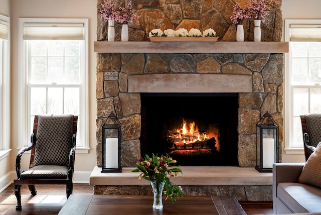 living area with a stone fireplace, baseboards, and wood finished floors