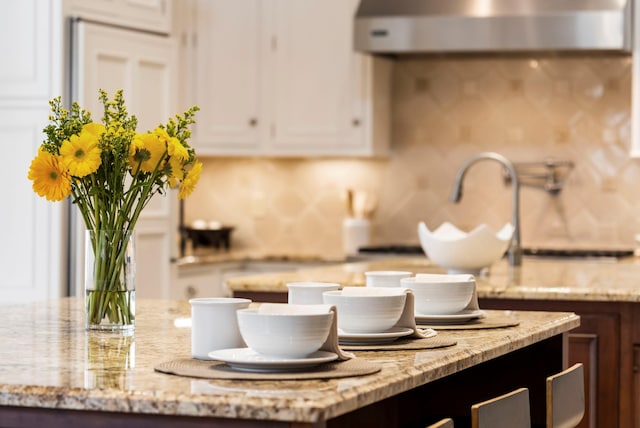 kitchen featuring light stone countertops, white cabinetry, and extractor fan