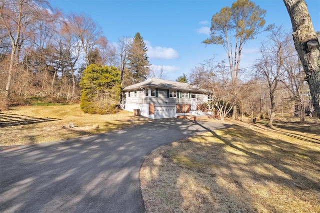 view of front of house with aphalt driveway, a front lawn, and a garage