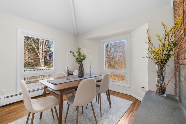 dining space featuring light wood-style flooring, baseboards, and vaulted ceiling