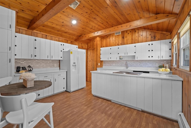 kitchen with visible vents, light wood-style floors, white fridge with ice dispenser, a baseboard radiator, and vaulted ceiling with beams