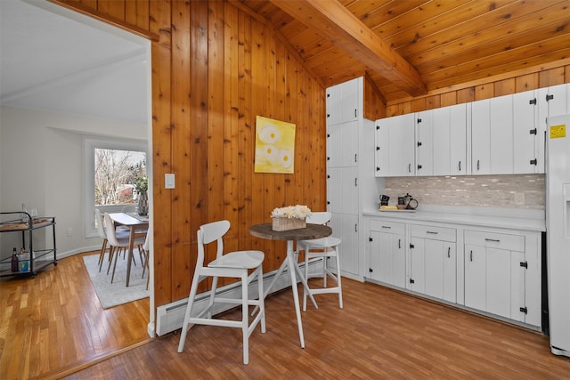 kitchen featuring lofted ceiling with beams, light wood-style flooring, decorative backsplash, light countertops, and white cabinets