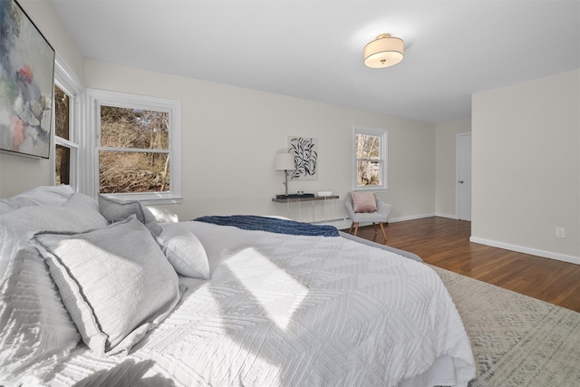 bedroom featuring a baseboard heating unit, wood finished floors, and baseboards