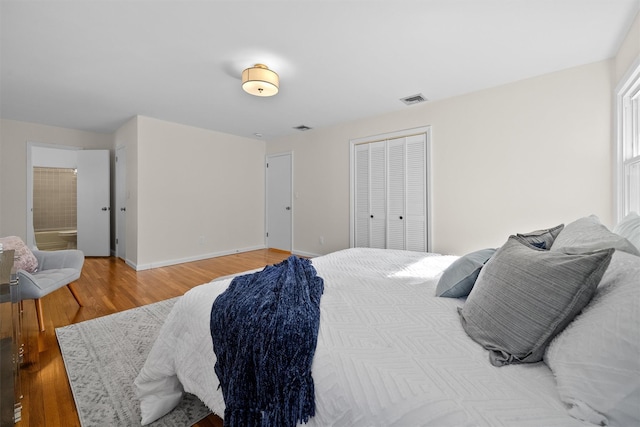 bedroom with baseboards, visible vents, a closet, light wood-type flooring, and connected bathroom